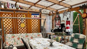 A covered patio area with a table set for dining, a bench, and a variety of items on shelves and tables. - Rügen-apartment 65 - apartment (Garz/Rügen)