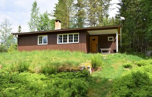 A single-story wooden cabin with a chimney, two windows, and a door.