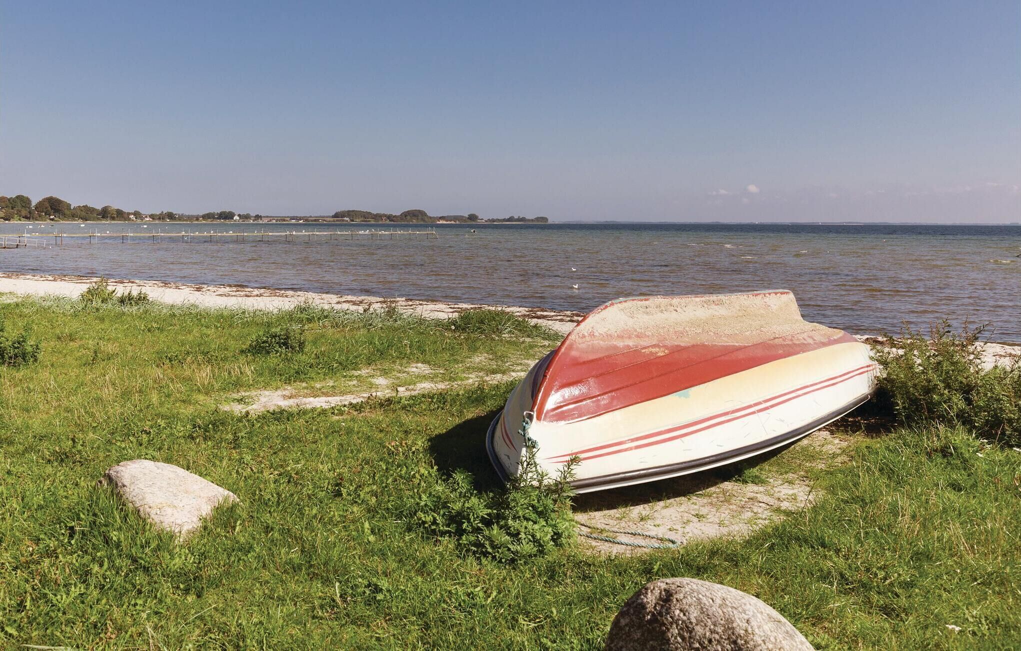 A boat on a grassy shore by a calm body of water.