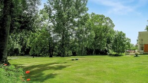A well-maintained grassy area with trees and a building in the background. - Beautiful home in La Barde (La Barde)