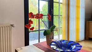 A room with a window, a radiator, a table with a vase, and a potted plant.