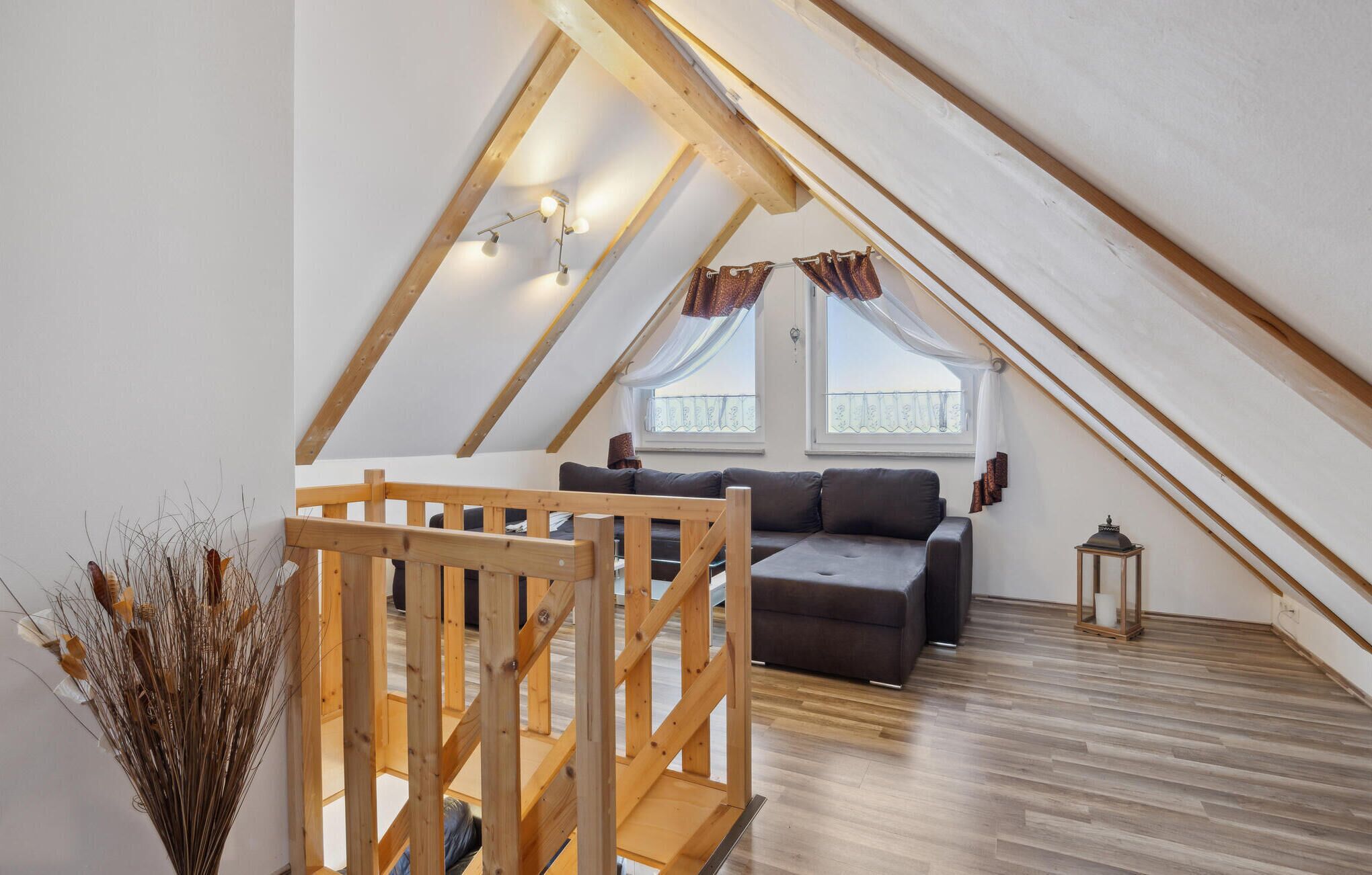 Un dormitorio acogedor en el ático con una escalera de madera, un sofá y una pequeña mesa.