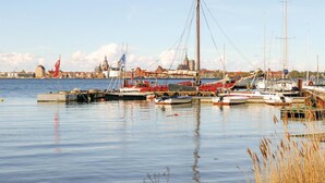 A harbor with various boats docked, a flag, and a cityscape in the background. - Ferienhaus 2 Altefähr (Altefähr/Rügen)