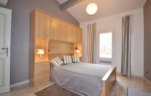 A bedroom with a bed, bedside lamps, a wooden wardrobe, and a window with curtains. - 1 bedroom awesome home in Visan (Visan)