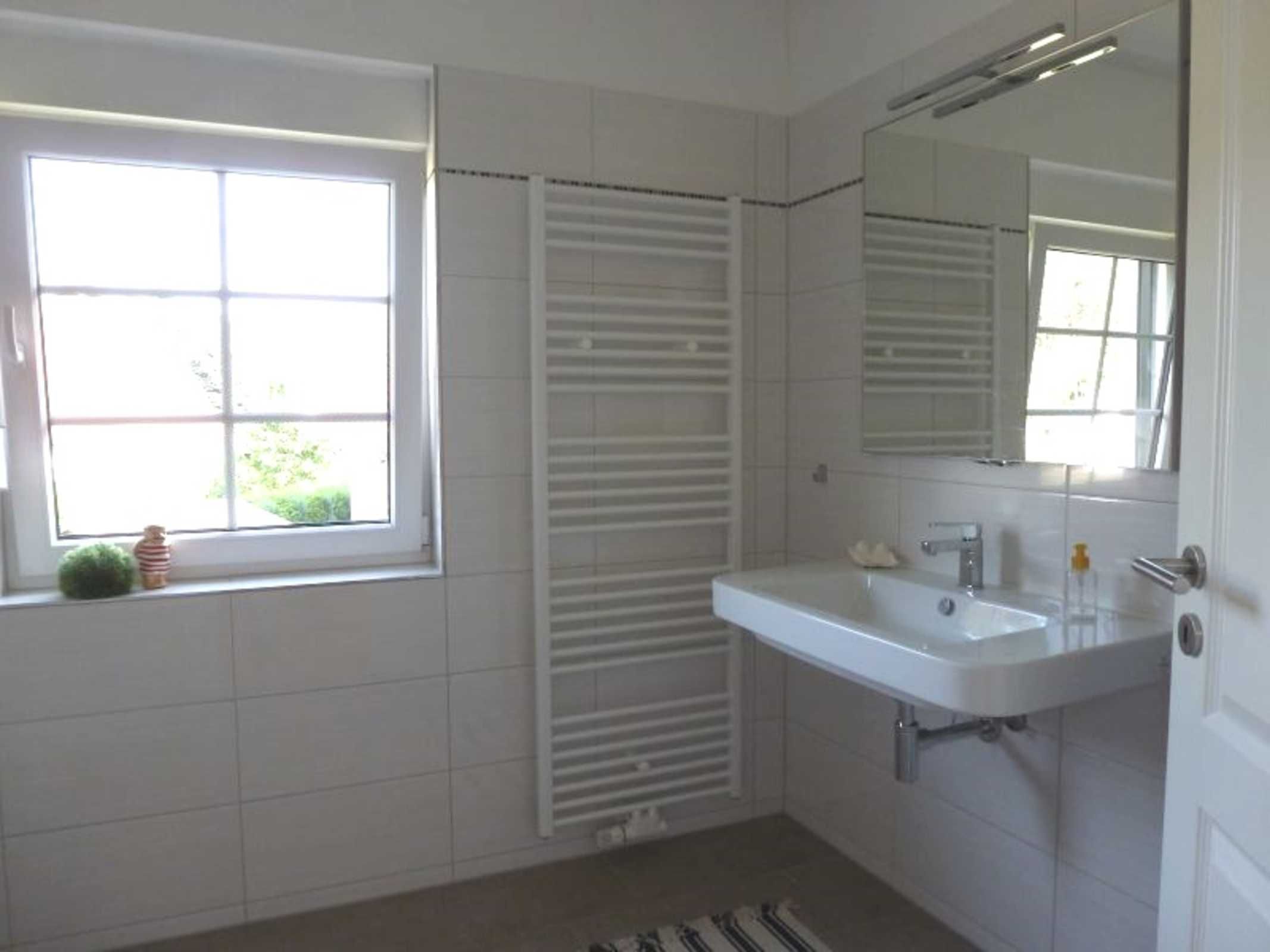 A bathroom with a window, a white sink, and a towel rack.