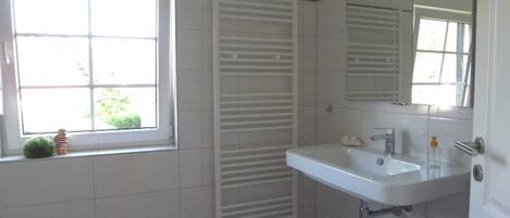 A bathroom with a window, a white sink, and a towel rack.