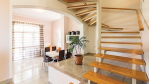 Un intérieur moderne avec un escalier en bois, un coin repas comprenant une table et des chaises, et une plante en pot.
