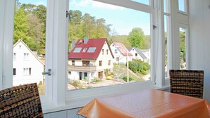 Quarto com uma grande janela que oferece vista para uma área residencial com casas e árvores.