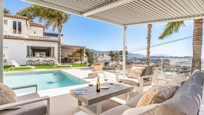 A poolside area with a view of the city, outdoor seating, and a covered patio. - Nice home in Almuñecar (Almuñecar)