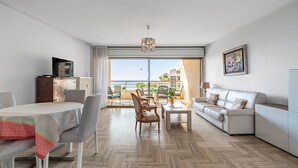 Ett modernt vardagsrum med en matplats, en soffa, en tv och utsikt över havet.