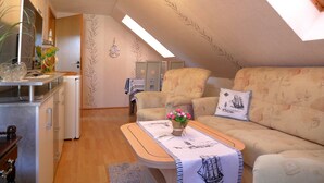 Una habitación acogedora estilo loft con techo alto, zona de comedor y sofá con cojines estampados.