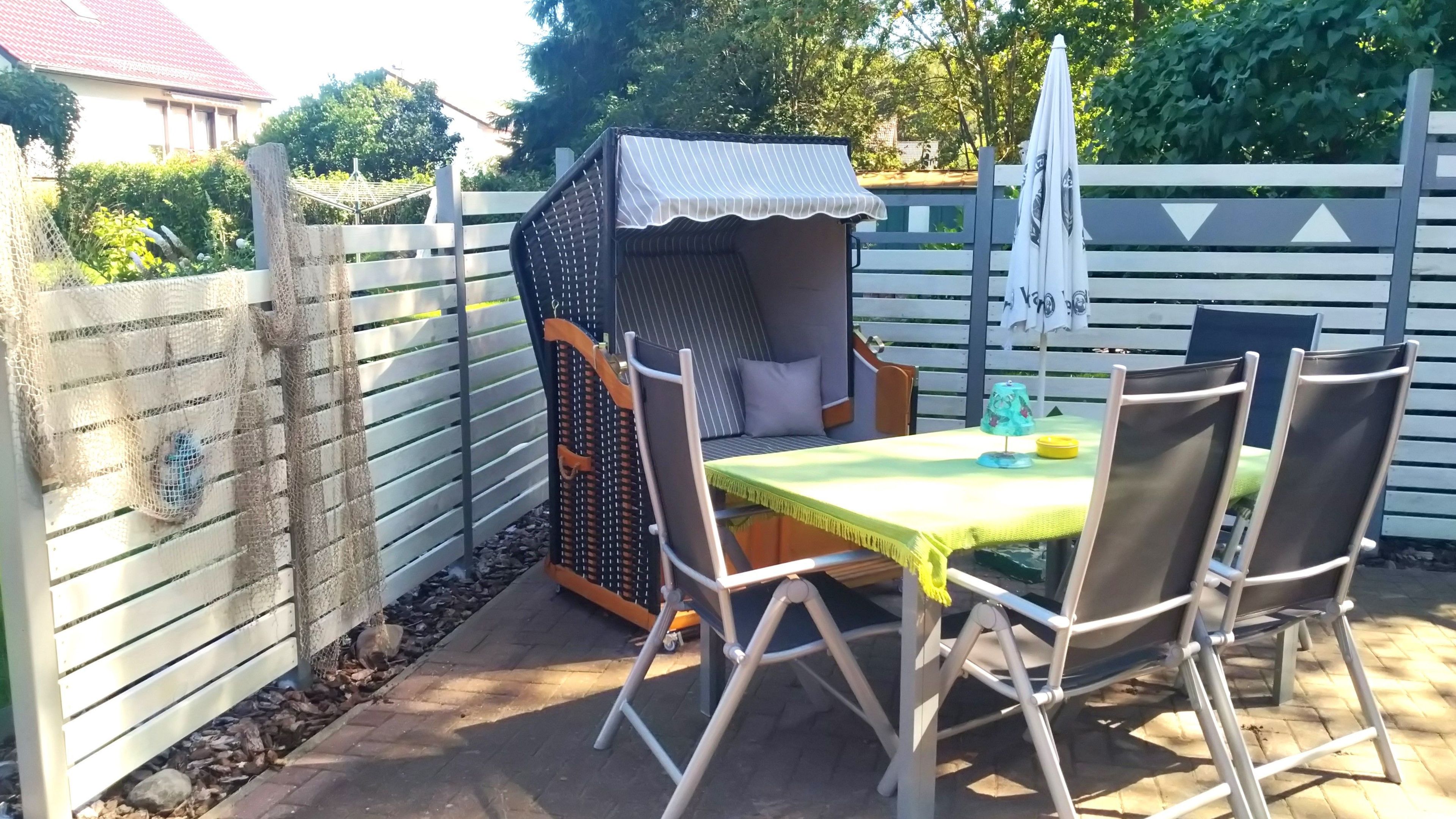 A patio area with a table and chairs, a small covered seating area, and a white fence.