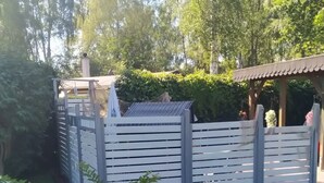 Un jardín con cerda de madera, un pérgola y diferentes plantas y flores.