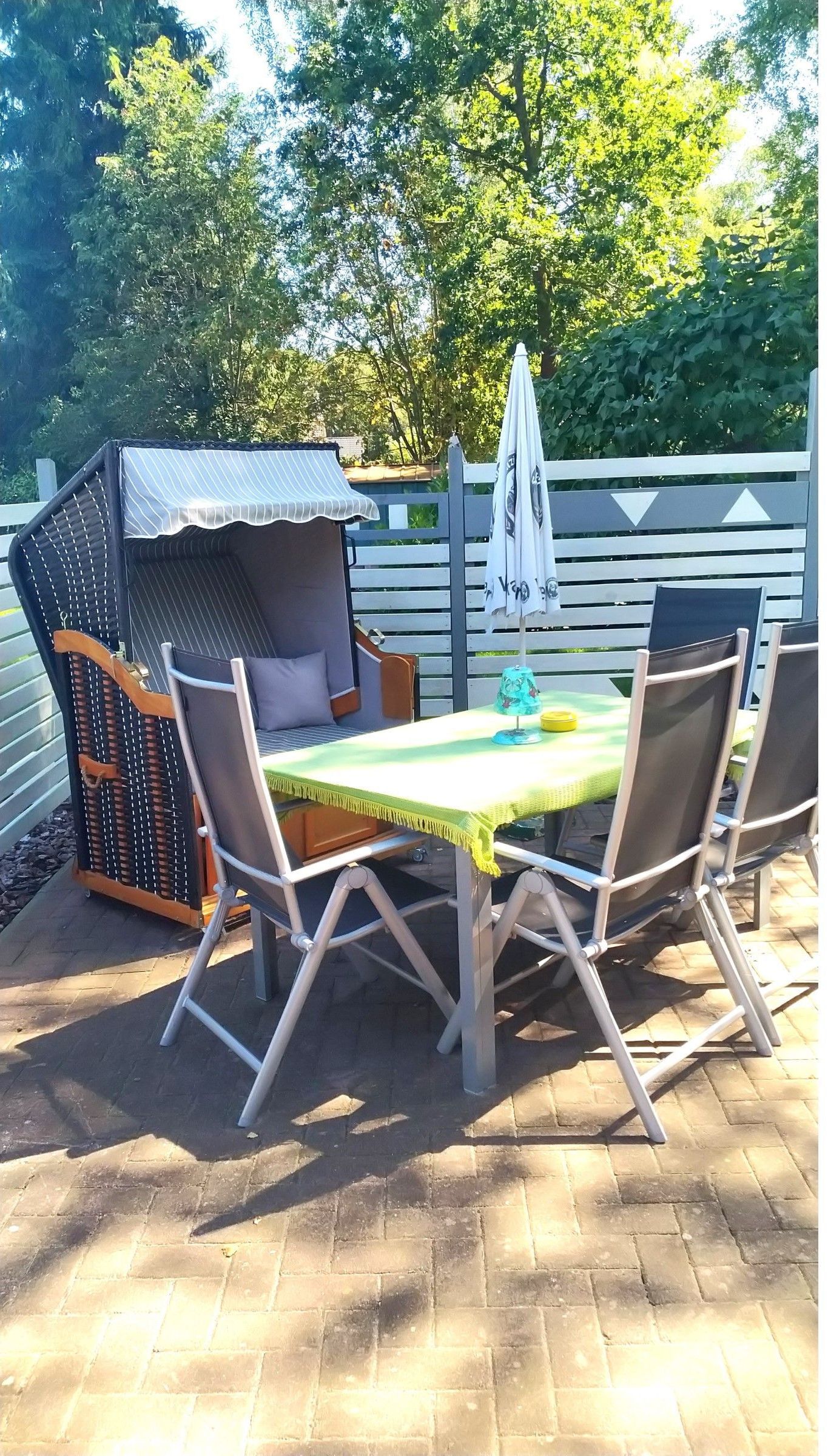 An outdoor patio with a table, chairs, and a grill structure.