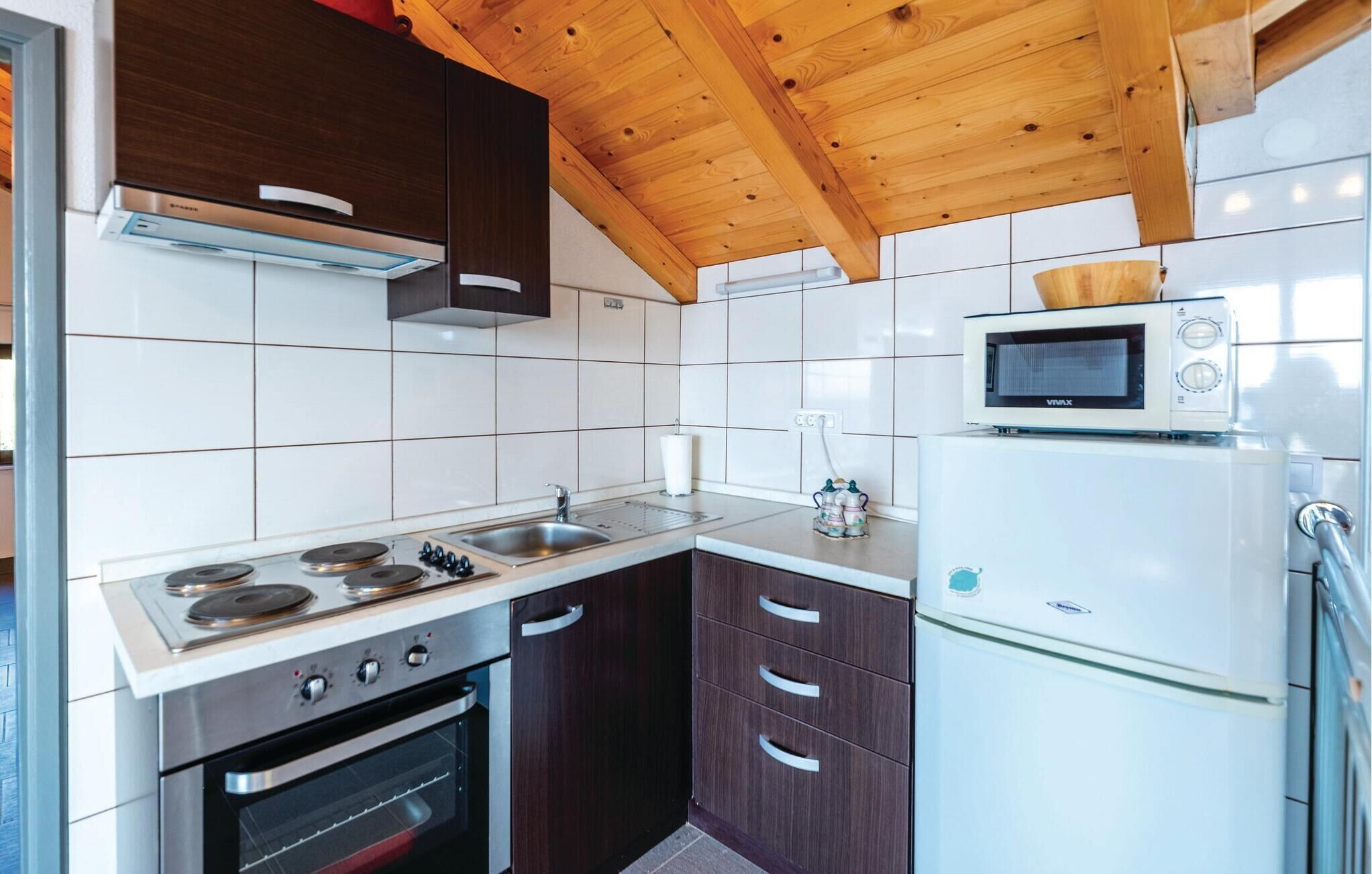 A compact kitchen with a stove, oven, microwave, and refrigerator.