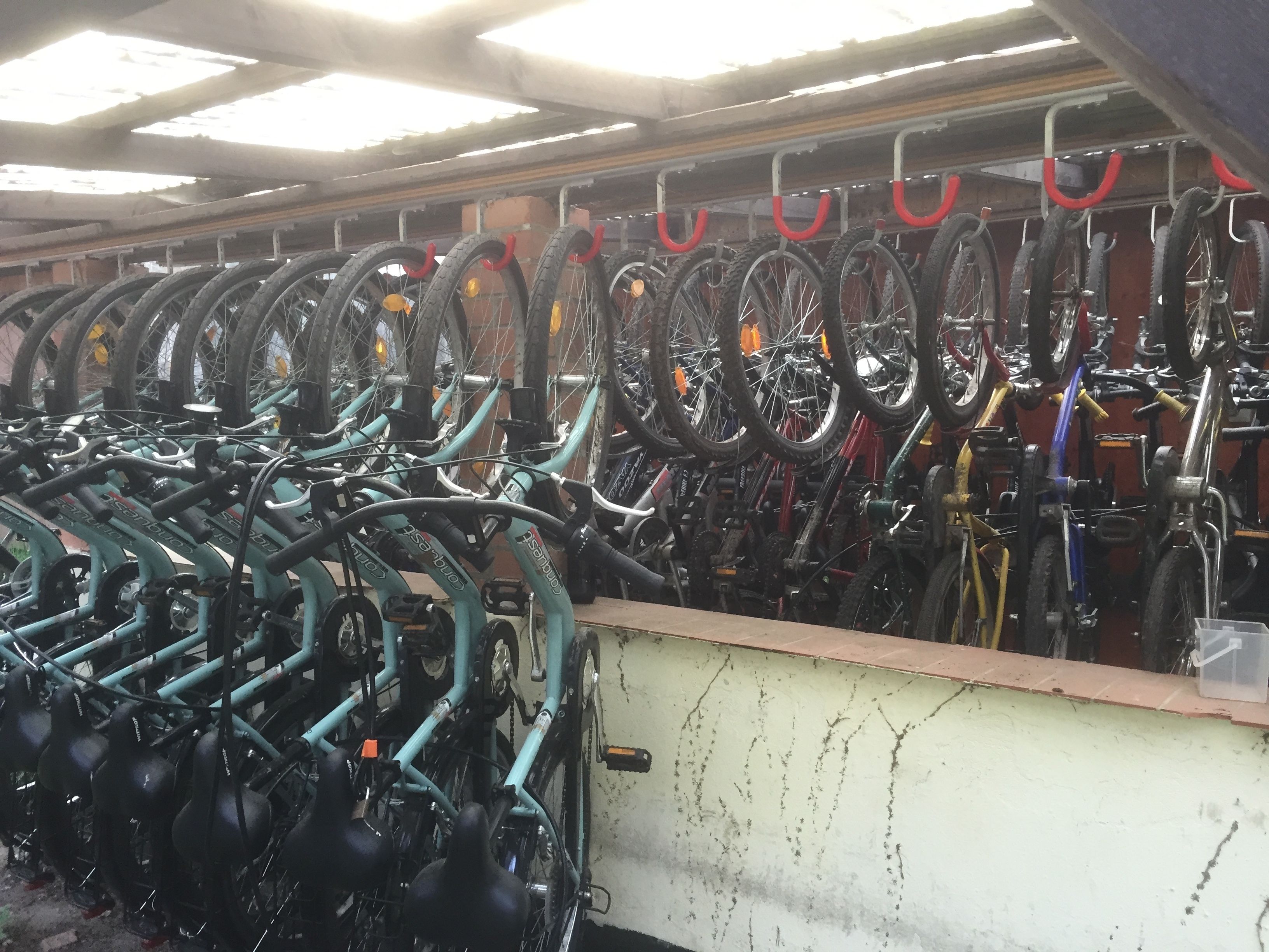 A bike rental station with multiple bicycles and red hooks for securing them.