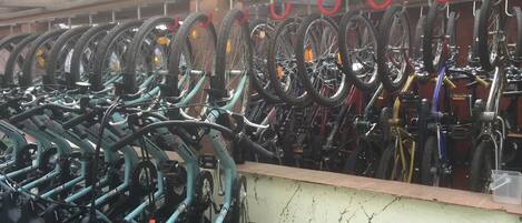 A bike rental station with multiple bicycles and red hooks for securing them.