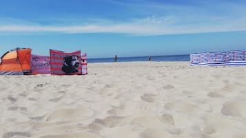 Une plage de sable avec des tentes et un parasol rayé.