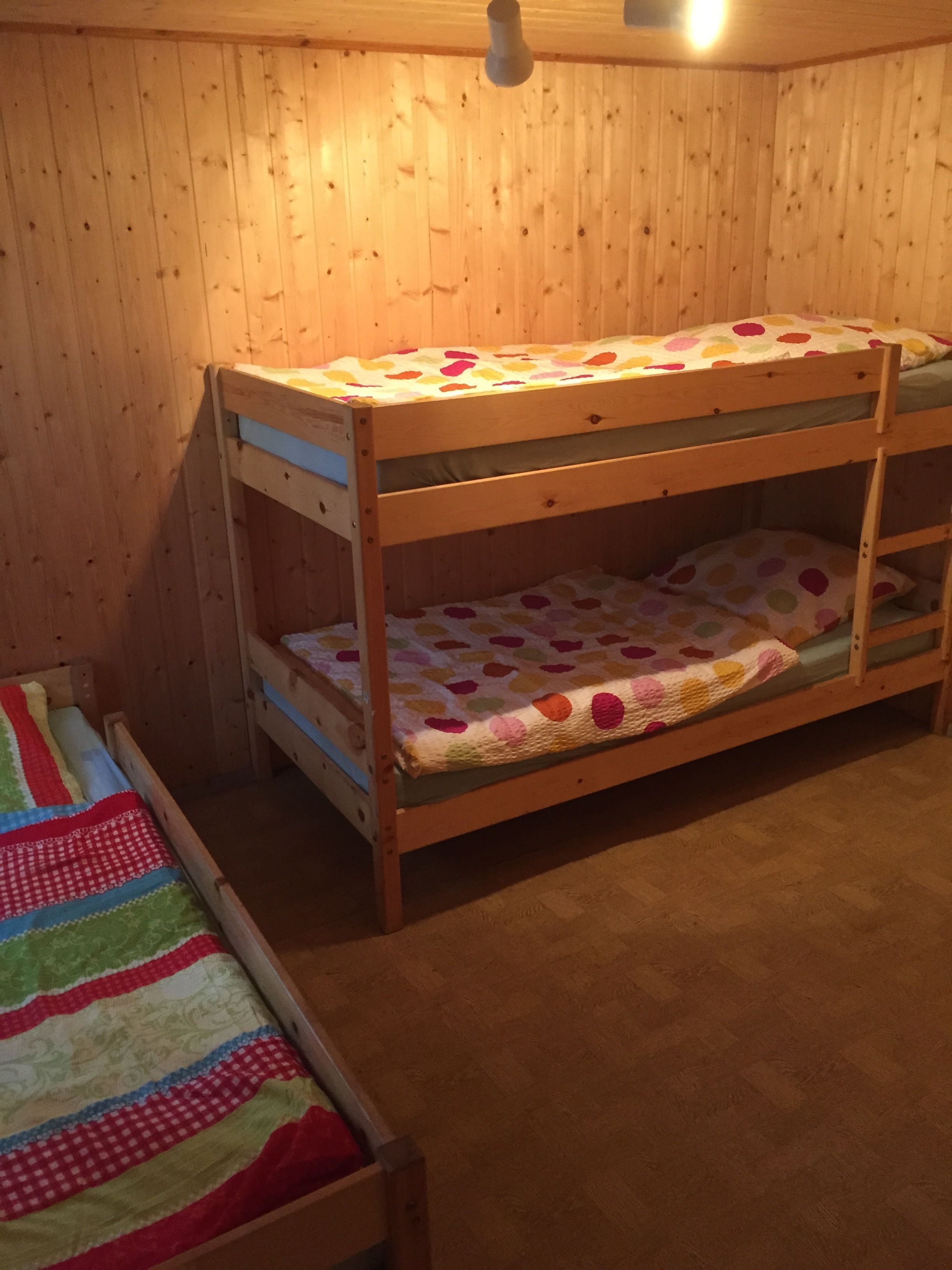 A bunk bed with a polka dot bedspread and a striped blanket on the lower bunk.