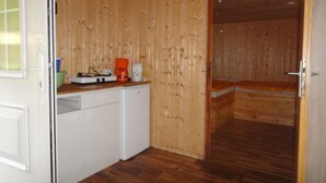 Una cocina compacta con paredes de madera, lavavajillas, estufa y cafetera.