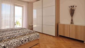 Ein Schlafzimmer mit Bett, Schiebetürenschrank und Blick ins Freie.
