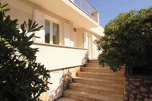 Staircase leads to a balcony with lush green surroundings.