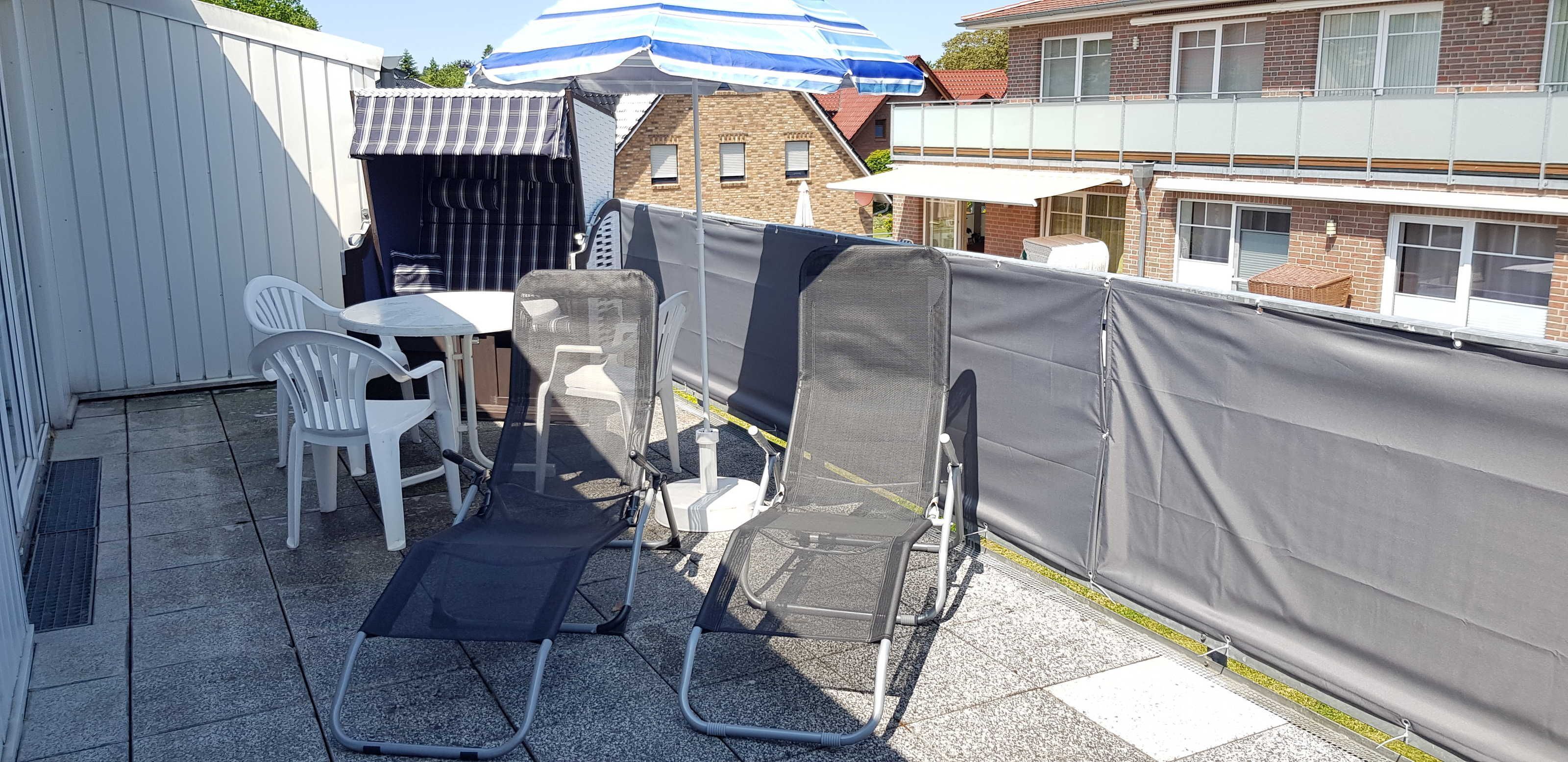 Een terras met tuinmeubilair, een overdekte zithoek en uitzicht op een woongebouw.