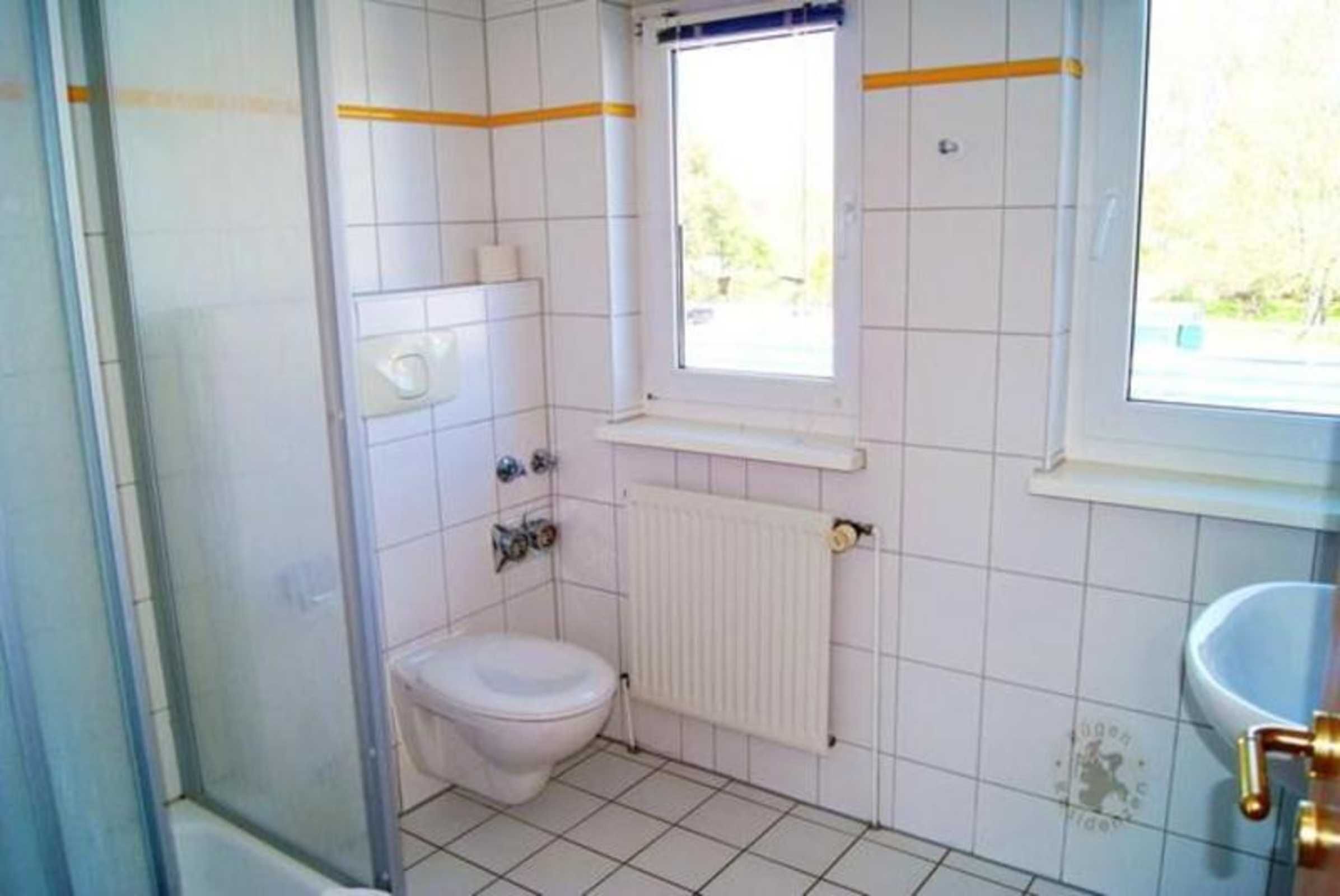 A small bathroom with a toilet, a window, and a radiator.