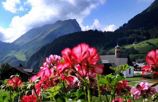 A mountain village with traditional architecture, a church, and lush greenery.