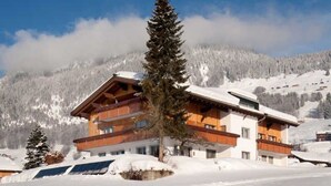 Ein mehrstöckiges Gebäude mit Holzfassade, großen Fenstern und einem Balkon.
