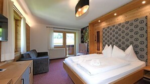 Ein Schlafzimmer mit einem Bett, einem Sessel, einem Schreibtisch und einem Fenster.