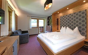 Ein Schlafzimmer mit einem Bett, einem Sessel, einem Schreibtisch und einem Fenster.
