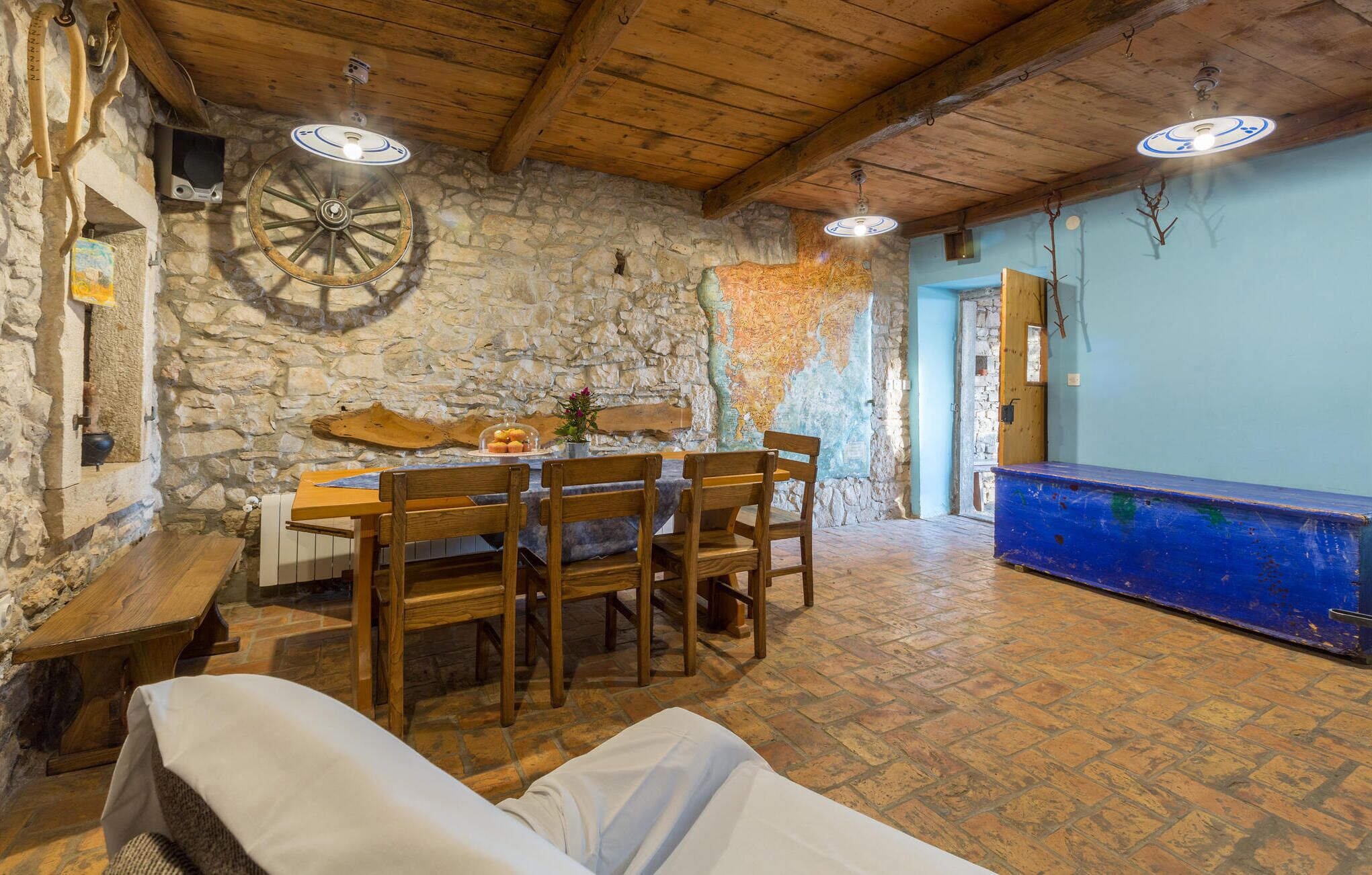 A rustic dining area with a stone wall, wooden furniture, and a large wooden table.