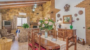 A cozy living room with a stone wall, wooden furniture, a fireplace, and decorative items.