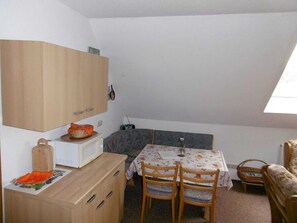 A small, cozy room with a wooden cabinet, a table with chairs, a radio, and a window. - Apartment - Rügen-Fewo 61 (Garz/Rügen)