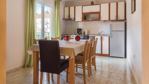 A compact kitchen with a dining table and chairs, a refrigerator, and cabinets. - Awesome apartment in Raslina with WiFi (Raslina)