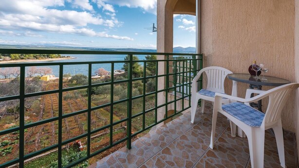 A balcony with a view of a lake and mountains, a table with chairs, and a bottle of wine. - Awesome apartment in Raslina with WiFi (Raslina)