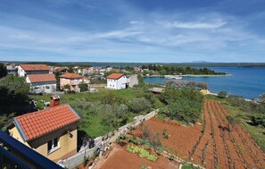 Ein Küstendorf mit terrassenförmig angelegten Weinbergen, Häusern mit roten Ziegeldächern und einem Hafen mit Booten.