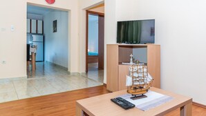 A living room with a wooden table, a ship model, and a television on a stand. - Awesome apartment in Raslina with WiFi (Raslina)