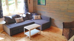 Ein gemütliches Wohnzimmer mit einem grauen Sofa, einem kleinen weißen Tisch und einem Korbstuhl.
