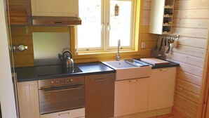 Eine kompakte Küche mit Herd, Backofen, Spülmaschine, Spüle und Holzschränken.