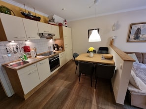 A compact kitchen with a dining area, wooden cabinets, a sink, and a dining table with chairs.