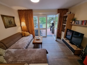 A living room with a sofa, a coffee table, a television, and a bookshelf.