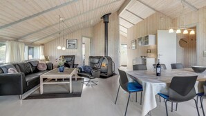 Un amplio salón con techo alto, chimenea, una mesa de comedor y muebles modernos.