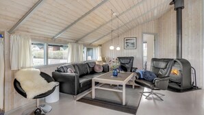 Un salón acogedor con un sofá de cuero negro, una mesa de centro blanca y una chimenea.
