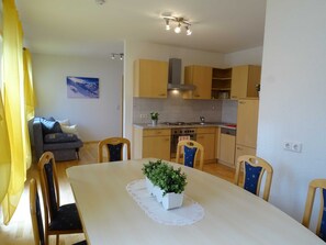 A compact kitchen with wooden cabinets, a dining table with chairs, and a potted plant on the table. - Apartment for 2-5 people - Alpine jewel (Laimach)
