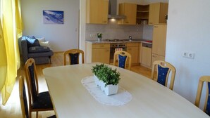 Une cuisine de taille réduite avec des meubles en bois, une table à manger avec des chaises et une plante en pot posée sur la table.