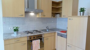 Une cuisine avec des meubles de couleur bois clair, une cuisinière en acier inoxydable, un four encastré, un évier et un lave-vaisselle.
