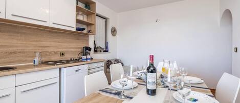 A modern kitchen with white cabinets, a wooden countertop, and a dining area set for a meal.