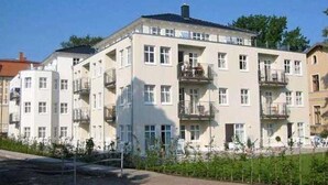 A multi-story residential building with balconies, a flat roof, and a clear sky. - Villa Aquamarina Whg. 8, TERRACE, CAR CHAIR - Villa Aquamarina, 1st ROW, partly. (Heringsdorf)